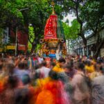 A bustling crowd gathers around a colorful chariot during the Ratha Yatra festival in Kolkata, India.