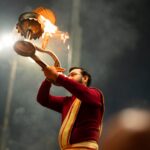 Hindu priest performs aarti ritual with sacred fire at Kumbh Mela in Prayagraj, India.