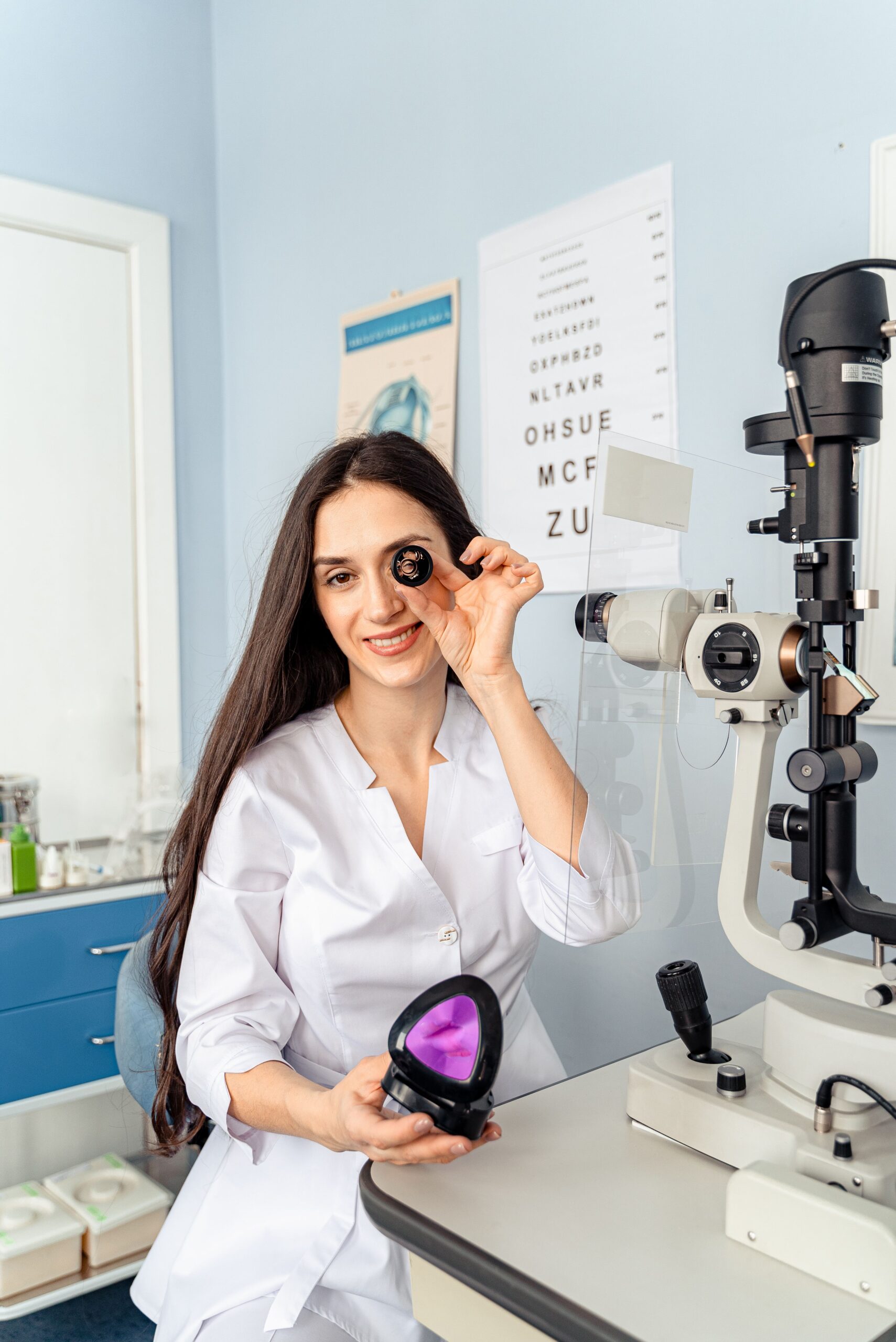 Smiling female optometrist holds lens in bright medical office.